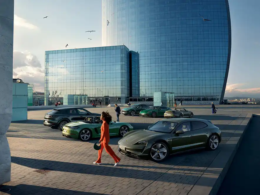 Une femme passe devant plusieurs modèles de Porsche de différentes couleurs.